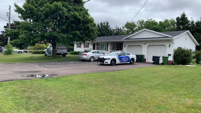 Deux véhicules de la police garés devant une maison.
