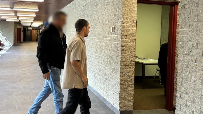 Deux personnes dans un couloir de palais de justice.