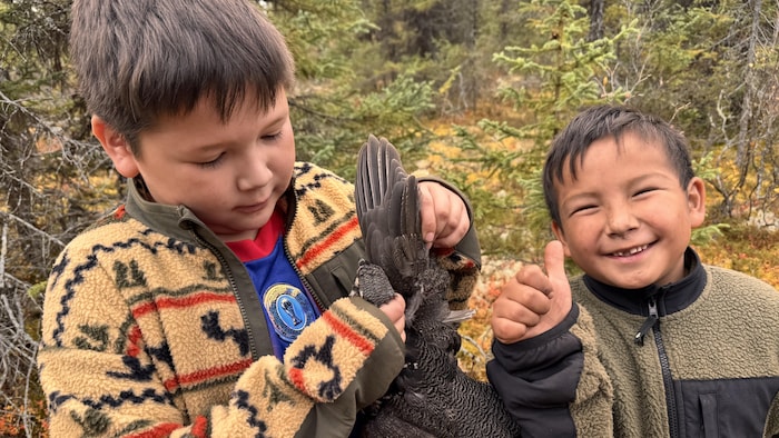Deux enfants plument une perdrix. 