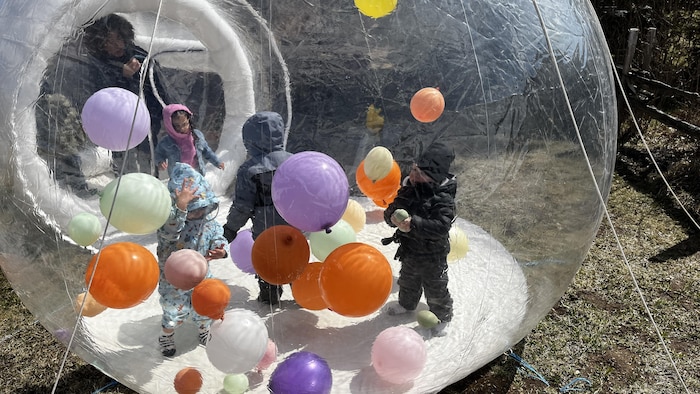 Des enfants jouent dans un jeu gonflable avec des ballons.