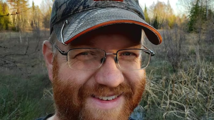 Jim Goodall portant des lunettes sourit.