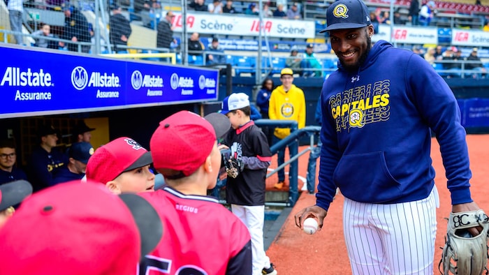 Il s'amuse avec des jeunes joueurs de baseball sur le terrain.