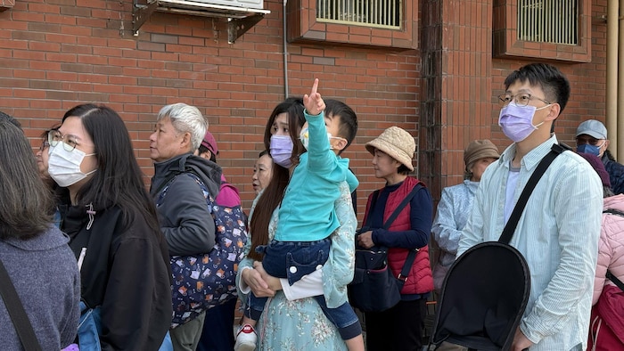 Che Zhu-Yun au milieu d'un groupe de personnes qui attendent pour entrer dans le navire.