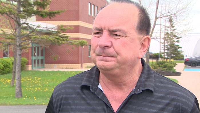 Louis Lebouthilier devant un immeuble de brique.