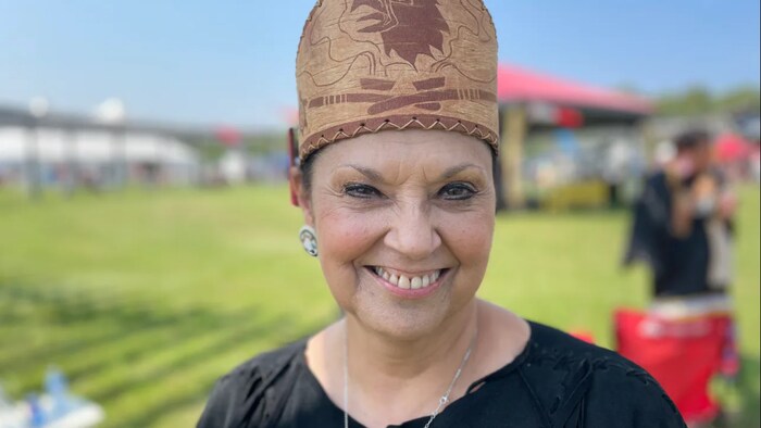 Une femme souriante qui porte une coiffe autochtone.