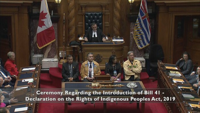 Les quatre représentants autochtones sont assis devant le président de l'Assemblée législative et écoutent le discours du chef de l'opposition.