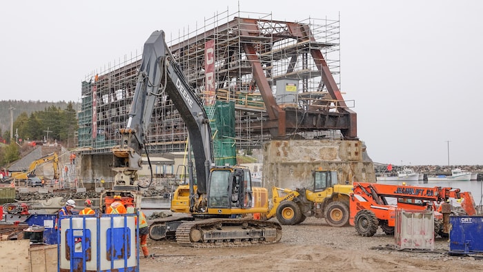 Un pont ferroviaire partiellement démantelé est entouré d'échafauds et de machineries de construction.