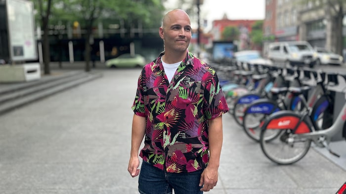 Un homme en chemise à fleurs devant une station bixi.