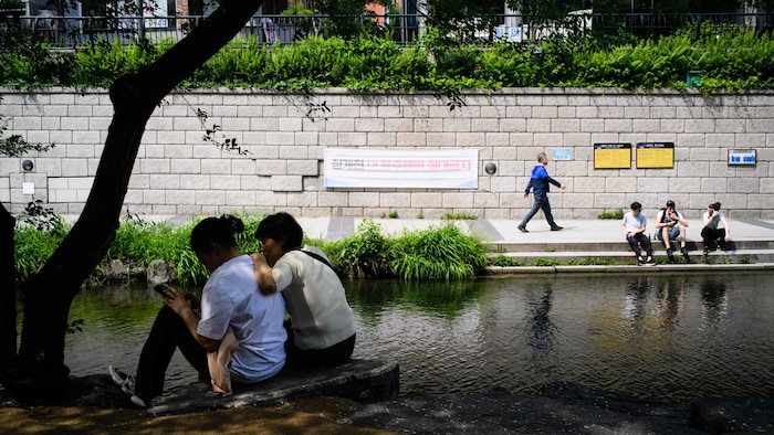 Des gens marchent ou sont assis aux abords du Cheonggyecheon, en mai 2023.