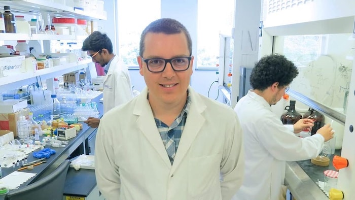 Un homme avec un sarrau pose dans un laboratoire.