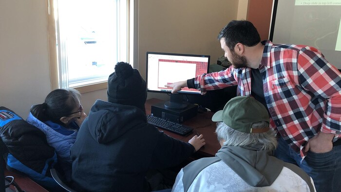 Quatre personnes travaillent inscrivent des données à l'ordinateur.