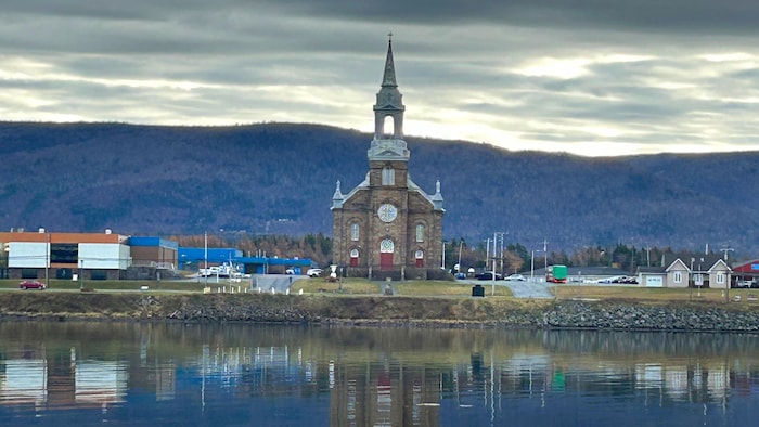 Une église photographiée le soir de l'autre côté de la rive se reflète dans l'eau.