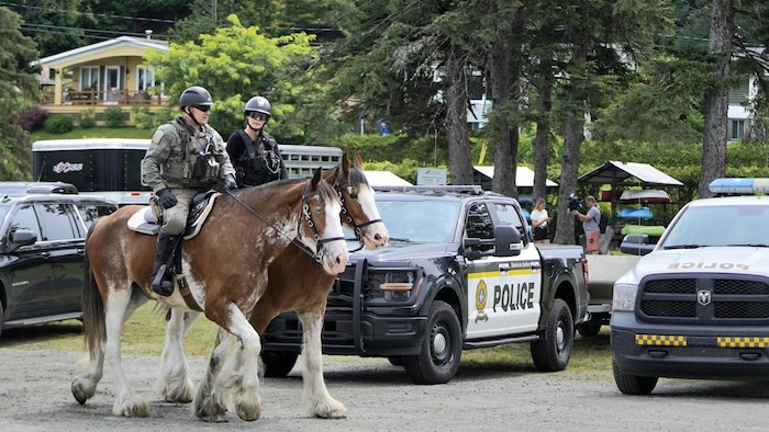 Des policiers à cheval près de véhicules de police.
