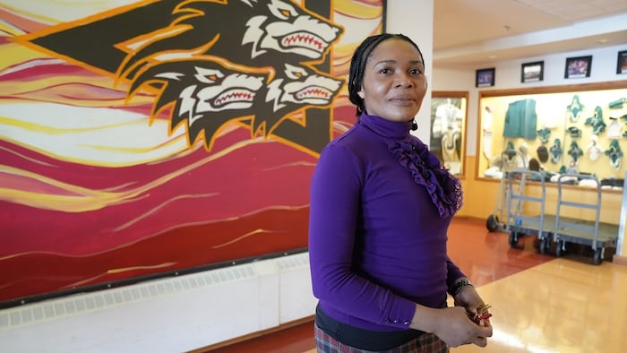 Un femme pose devant la caméra dans le corridor d'une école. 