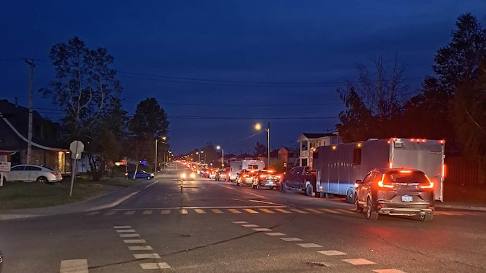 Des voitures en file qui quittent la ville de Chibougamau en soirée.