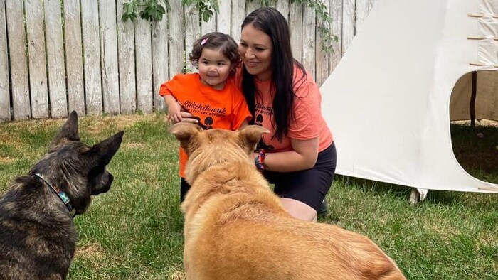 Une mère et sa fille devant deux chiens.