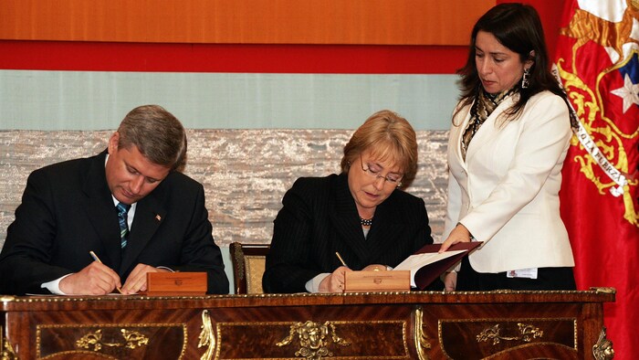 Santiago, CHILE: Canadian Prime Minister Stephen Harper (L) and Chilean President Michelle Bachelet sign an agreement in the framework of the tenth anniversary of the Free Trade Agreement between Chile and Canada, in Santiago de Chile, on July 17th, 2006. 