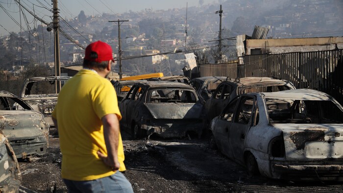 A man looks at burning vehicles after a fire broke out in the hills of Viña del Mar, Chile, February 3, 2024.