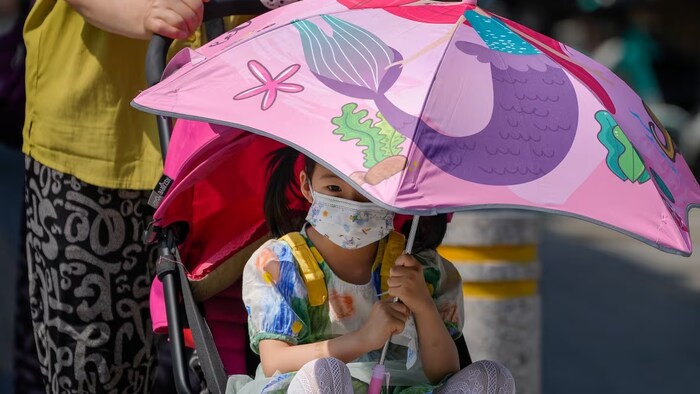 A child uses an umbrella to shield from the sun in Beijing during a heatwave in June this year. (Andy Wong/The Associated Press)