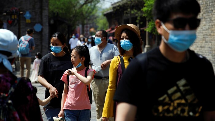 Des gens portant des masques visitent un site touristique en Chine.