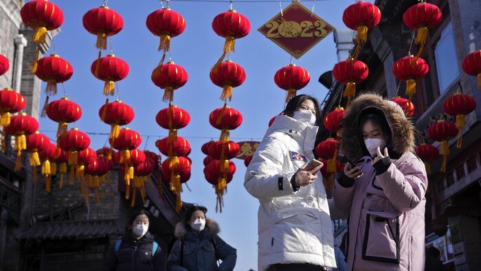 Deux femmes sous une enfilade de lanternes chinoises et une affiche sur laquelle on peut lire « 2023 ».