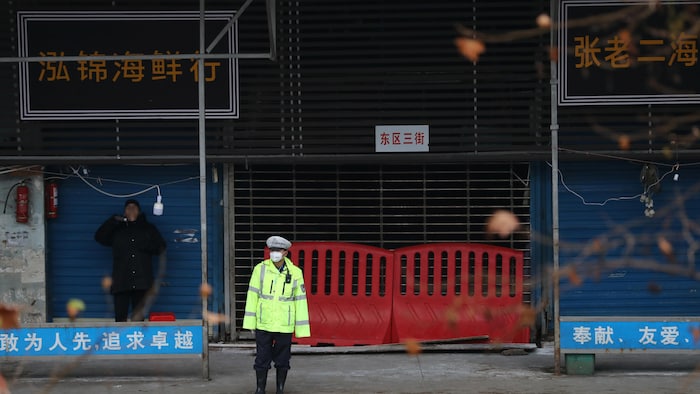 Un agent de police devant la grille du marché aux fruits de mer de Wuhan.