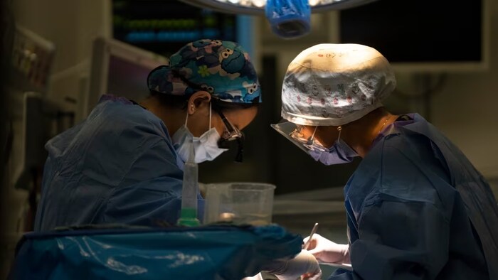 Deux chirurgiennes effectuent une opération dans une salle opératoire.