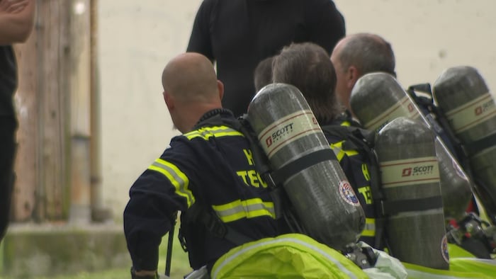 Des travailleurs des services d'urgence avec des bombonnes d'oxygène sur le dos. 