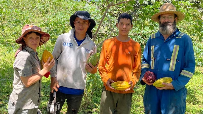 Kristen Krash, cofondatrice de Choco Estates, tient une cabosse de cacao en Équateur, aux côtés des agriculteurs Daniel Figueroa, David Figueroa et Robert Payant, originaire d'Assiniboia, en Saskatchewan.