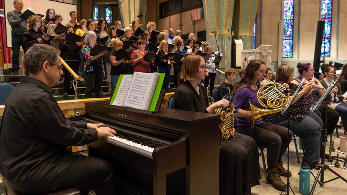 Des musiciens assis devant les membres d'une chorale.