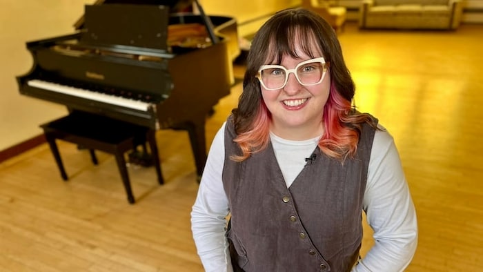 Hannah Bayne est debout devant un piano.