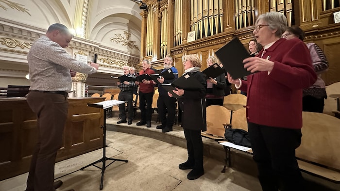 Plusieurs choristes chantent avec leurs livres.