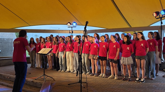 Le chœur de filles chante sous la tente jaune de Sept-Îles.