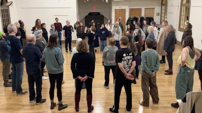 Un groupe de personnes, debout, en cercle en train de chanter.