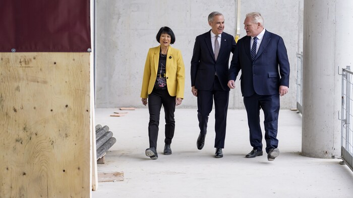 Les trois personnes marchent dans un chantier de construction.
