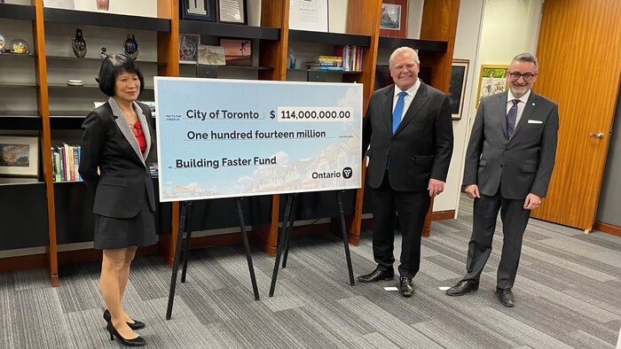 La mairesse Olivia Chow, le premier ministre Doug Ford et le ministre Paul Calandra sourient à côté d'un énorme chèque de 114 millions.