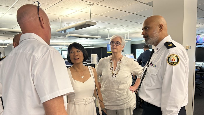 La mairesse Olivia Chow et Shelley Carroll, présidente du Conseil des services de police et le surintendant de la police de Toronto, Greg Watts, au centre de communication 911 du Service de police de Toronto.