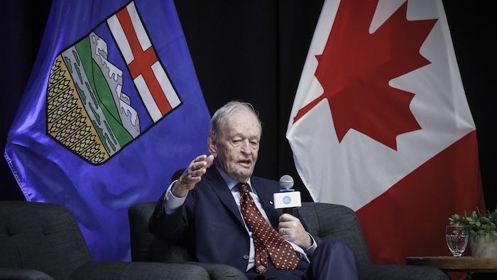 Jean Chrétien est assis devant des drapeaux albertain et canadien à une conférence de l'Université de Calgary le 12 juin 2025.