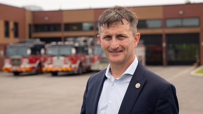 Chris Ross devant une caserne de pompiers.