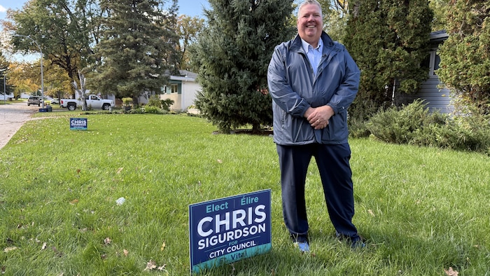 Chris Sigrudson à côté de sa pancarte