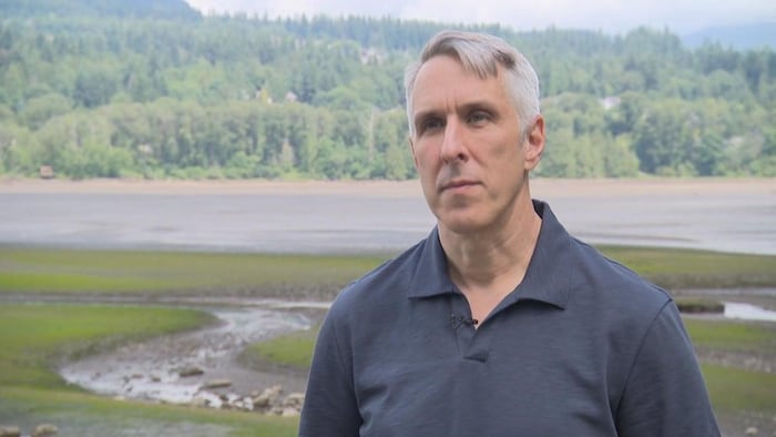 Un homme, Chris Tait, devant un paysage marécageux à l'orée d'une forêt.