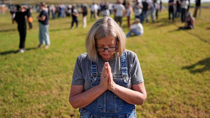 Une femme prie, les deux mains contre la poitrine.