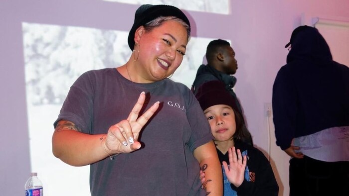 Une mère et son fils font des signes de main pour la caméra.