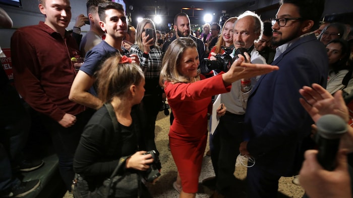 Christia Freeland, entourée de partisans et de photographes, salue la foule. 