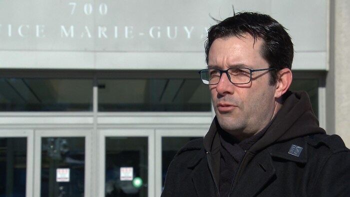 Christian Daigle accorde une entrevue à Radio-Canada à l'extérieur, en hiver, devant l'édifice Marie-Guyart.