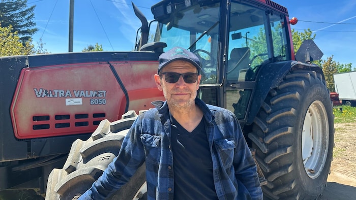 Un homme devant un tracteur.