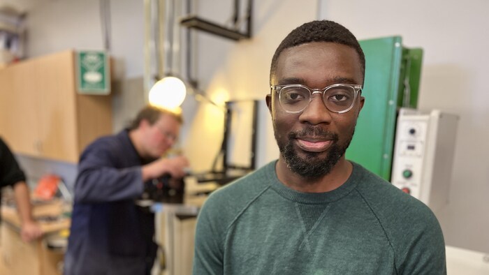 Un homme regarde la caméra dans une classe de cégep. 
