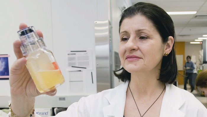 Une femme tient un échantillon d'urine. 
