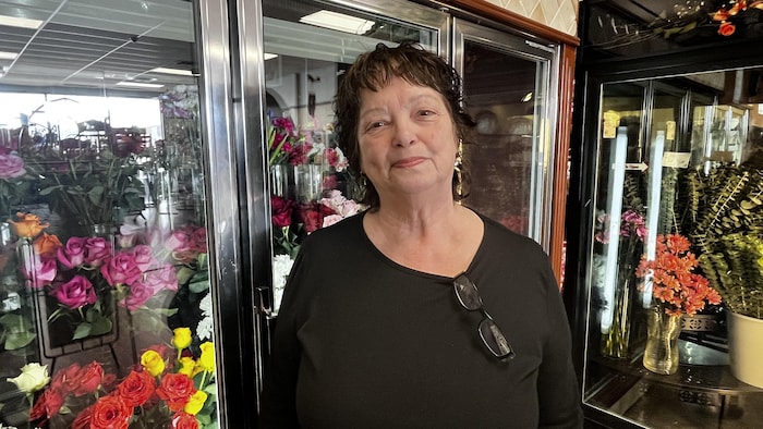 Un femme devant des présentoirs de fleurs.
