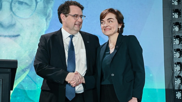 Christine Fréchette et Bernard Drainville se serrent la main sur scène.